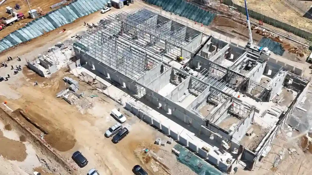 Vista aérea de dron que muestra el progreso de las obras de la megacárcel Cacco en Costa Rica, con múltiples edificios en construcción y maquinaria pesada operando.