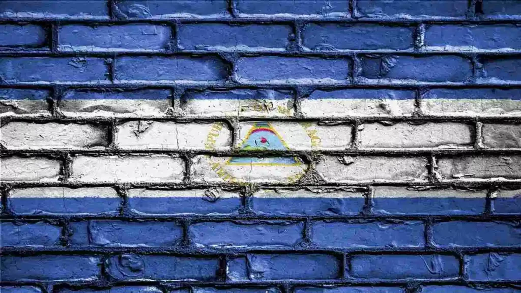 Bandera de Nicaragua pintada sobre un muro de ladrillos desgastado simbolismo de la crisis en Nicaragua