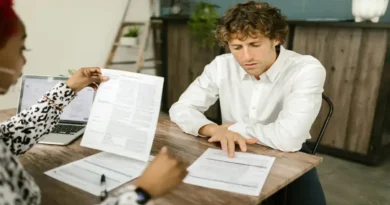 Costa Rica registra 154 mil personas desempleadas: entrevista laboral de un hombre revisando documentos en una oficina moderna, representando la búsqueda de empleo tras las cifras del INEC