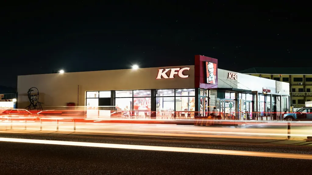 Fachada iluminada de un restaurante de comida rápida que ilustra cómo KFC desembarca en Nicaragua con sus nuevas sucursales.