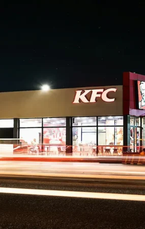 Fachada iluminada de un restaurante de comida rápida que ilustra cómo KFC desembarca en Nicaragua con sus nuevas sucursales.