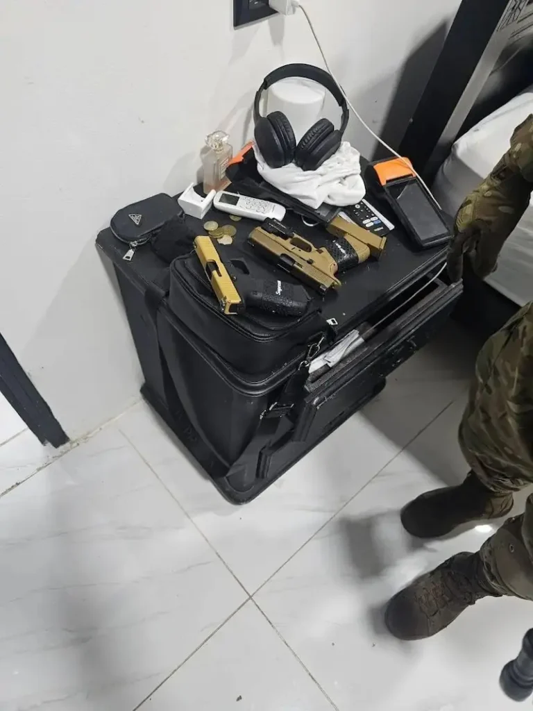 Pistolas de color dorado y negro decomisadas como evidencia en una habitación durante el operativo judicial contra la red narco.