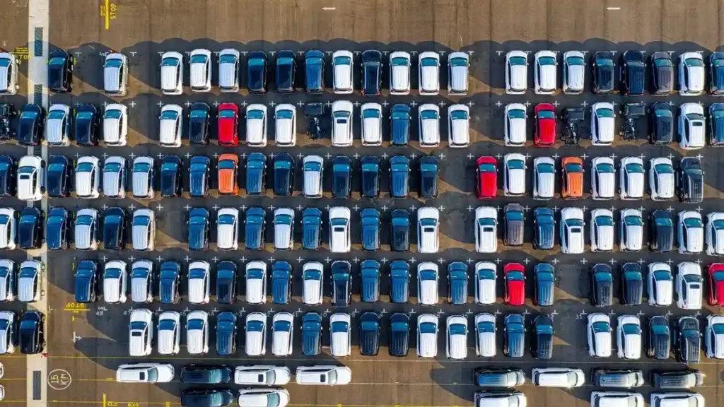 Vista aérea cenital de un gran lote de automóviles de diferentes colores estacionados y ordenados en filas, ilustrando el inventario de vehículos decomisados al narcotráfico.