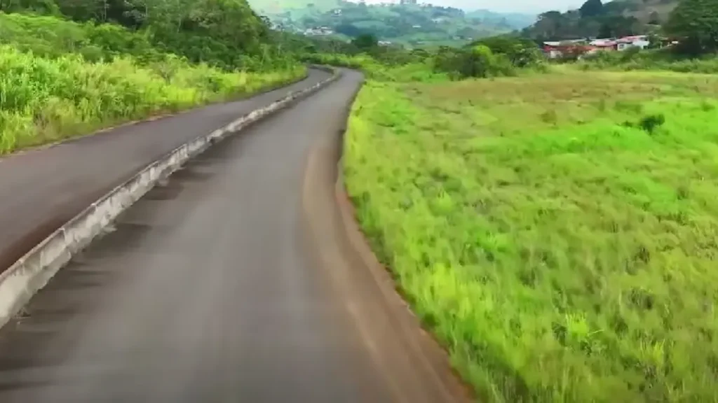 Tramo pavimentado con cuneta de concreto y áreas verdes laterales en el proyecto de la Carretera a San Carlos.