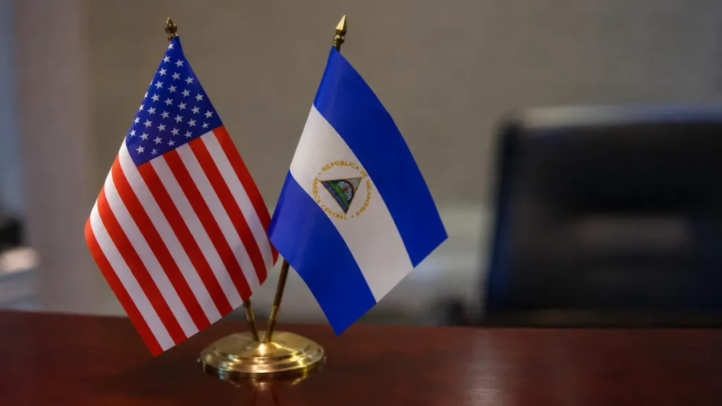 Pequeñas banderas de escritorio de Estados Unidos y Nicaragua colocadas sobre una mesa de madera durante los anuncios de sanciones a funcionarios nicaragüenses.